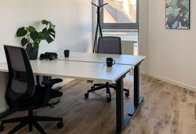 Minimalist office space with wooden floors, a large white desk, and green wall art.