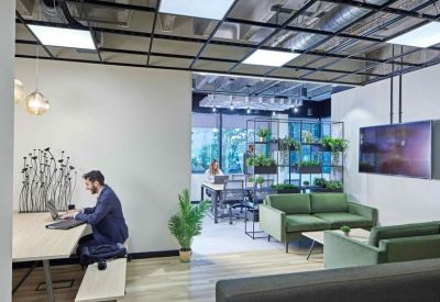 Modern coworking space with a mix of desk seating and plush green velvet sofas.