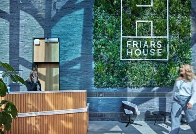 Reception area featuring a wooden desk against a vibrant living green wall and blue tiled backdrop.