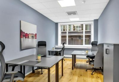 Private three-person office suite with grey desks and natural light from a large window.