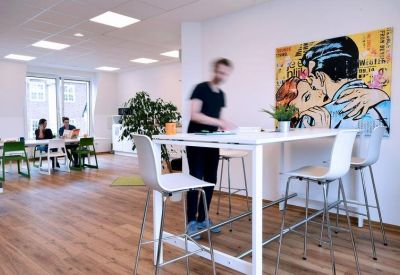 Modern coworking space with high-top tables, bar stools, and pop-art wall decor.