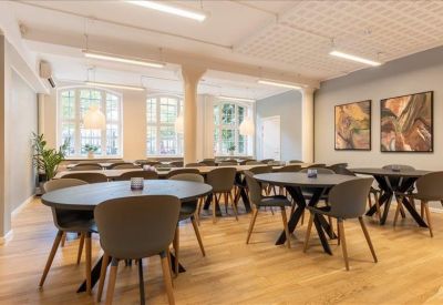 Spacious dining area with several round grey tables and abstract wall art.