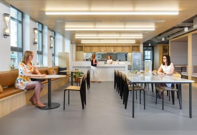 Bright communal dining area with long tables and modern strip lighting.