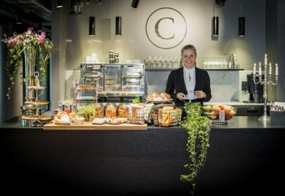 Professional reception desk with a branded wall, floral arrangements, and a smiling host.
