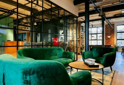 Lounge area with plush green velvet sofas and a black-framed glass partition.