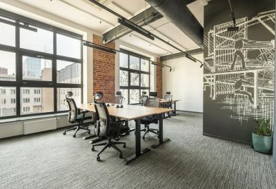 Spacious coworking area with long desks, ergonomic chairs, and a large chalkboard mural.