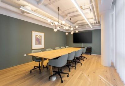 Professional meeting room with a long wooden table, grey chairs, and a minimalist chandelier.