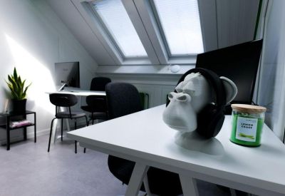 Bright office nook with white desks, slanted ceilings, and a decorative white monkey head.