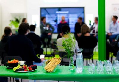 Group presentation or workshop taking place in a bright communal space with a large screen.