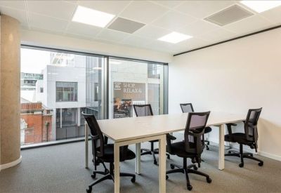 Professional four-person office suite with large windows and ergonomic mesh chairs.