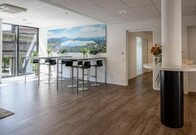 Bright communal break area with high tables and a large scenic wall mural.