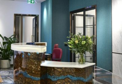 Sleek marble reception desk with blue resin detail and floral arrangement.