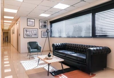 Modern lounge area with a black tufted leather sofa, teal armchair, and framed wall art.