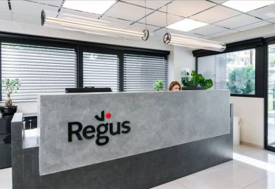 Sleek concrete reception desk featuring the company logo under modern overhead lighting.