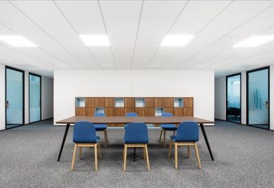 Spacious communal area with a long wooden table and blue upholstered chairs.
