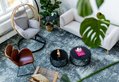 Bright lounge area featuring a hanging wicker chair, white sofa, and monstera plant.