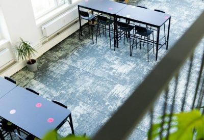 Spacious open coworking area with long black tables and ample natural light.