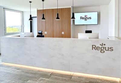 Modern white reception desk with wood paneling and Regus branding.