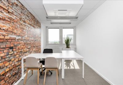 Bright private office featuring a rustic brick feature wall and white L-shaped desk.