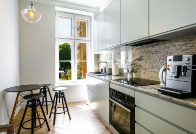 Bright communal kitchen with white cabinetry, a small breakfast table, and a built-in coffee machine.