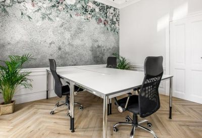 Bright four-person office suite featuring a floral accent wall and chevron pattern hardwood floors.