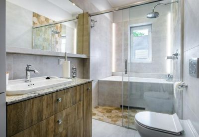 Modern bathroom featuring a glass shower, soaking tub, and a wood-finish vanity with a large mirror.