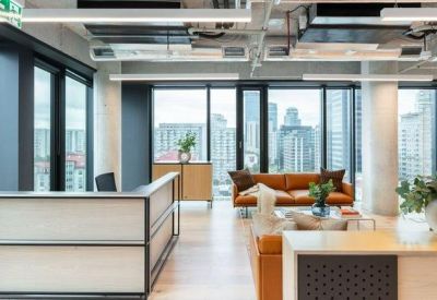 Modern reception lobby featuring a leather sofa and large windows overlooking Warsaw skyscrapers.