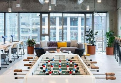 Vibrant breakout space with a foosball table, lounge seating, and dedicated coworking desks.