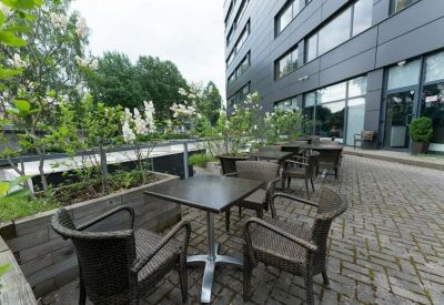 Outdoor seating area with tables and chairs surrounded by greenery.