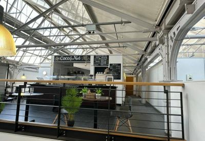 Mezzanine cafe and breakout area under an industrial glass roof with plants.