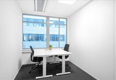 Small private office with a white standing desk and black chairs.