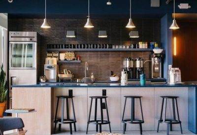 Sleek office kitchen and coffee bar with blue counters and black bar stools.