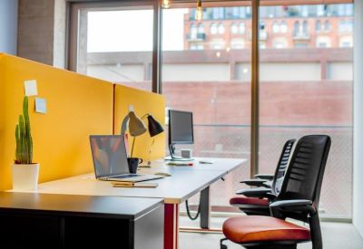 Bright workstation with a yellow privacy screen, colorful ergonomic chairs, and a potted cactus.