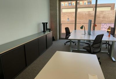 Minimalist office area with a long dark storage credenza and desks facing floor-to-ceiling windows.