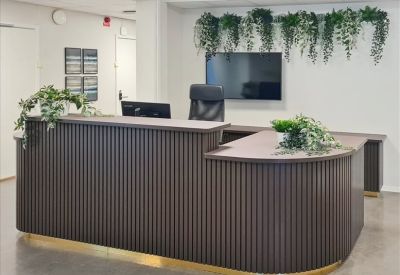 Reception area featuring a dark wood slatted desk and hanging greenery.