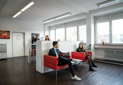 Professional breakout area with modern red lounge chairs and partitioned privacy walls.
