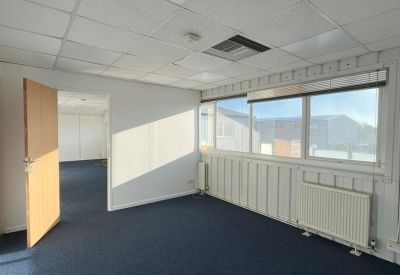 Spacious open-plan office area with blue carpeting and large windows providing natural light.