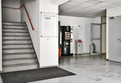 Building entrance area with a staircase, red handrail, and vending machine.