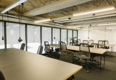Professional meeting room with large tables, mesh chairs, and an industrial-style ceiling.