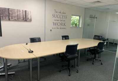 Meeting room with a long wooden table and a motivational wall decal.