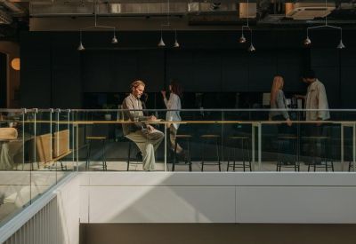 Upper-level break area with a glass railing and people working.