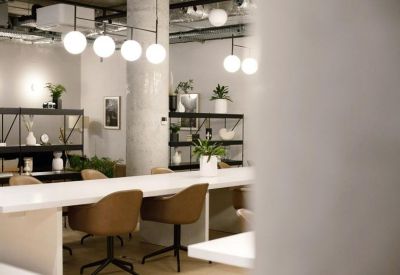 Open-plan office with long white desks and warm lighting.