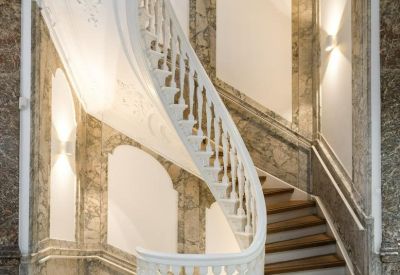 Grand marble lobby featuring an ornate white spiral staircase and decorative plasterwork.