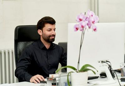 Modern workspace featuring a man at a desk with a blooming orchid and computer monitor.