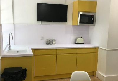 Communal kitchen area featuring vibrant yellow cabinetry and a round wooden table.