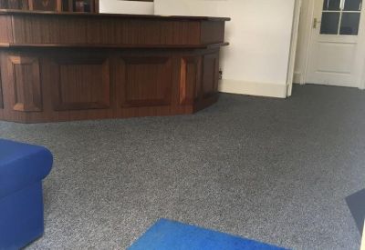 Reception area with a dark wood service desk and blue carpet accents.