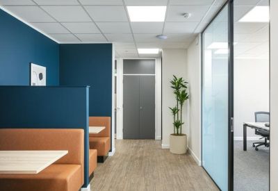Modern hallway featuring built-in orange booth seating and a glass-walled private office.