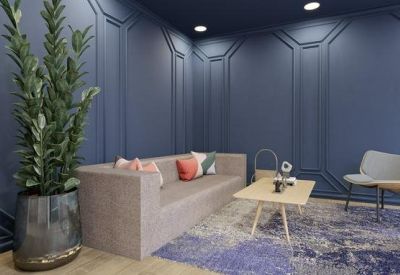 Modern lounge area with a grey sofa, blue wood-paneled walls, and a designer accent chair.