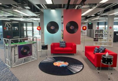 Music-themed breakout area with red sofas, record-shaped rug, and vinyl wall decor.