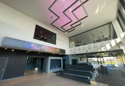 Spacious modern lobby with high ceilings, geometric lighting, and a tiered seating area.